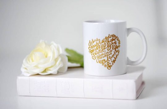 A white coffee mug with gold heart on it.