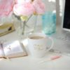 A cup of coffee on the table with some flowers