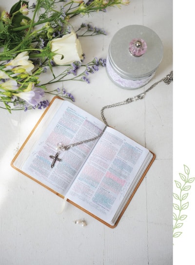 A bible and cross on the table with flowers.