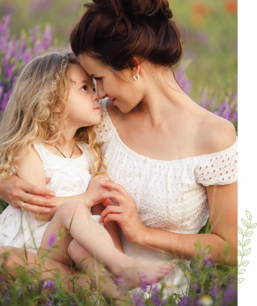 A woman and child in the grass with purple flowers.