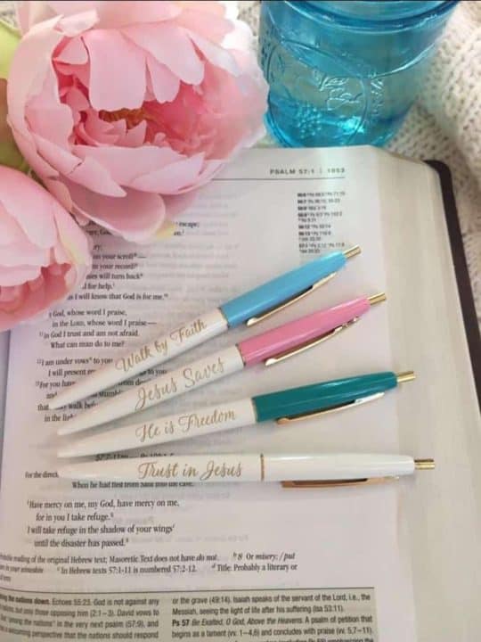 A book with four pens on it and some flowers