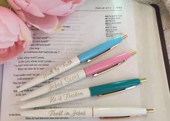 A book with four pens on it and some flowers