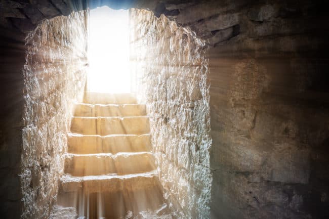 A light shining through the window of an old stone building.