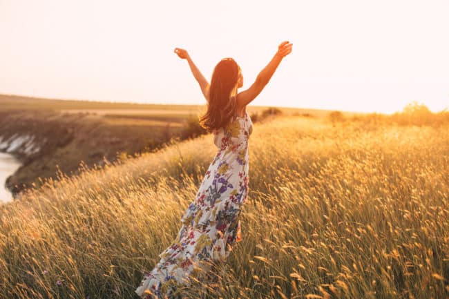 A woman in a field with her arms outstretched.