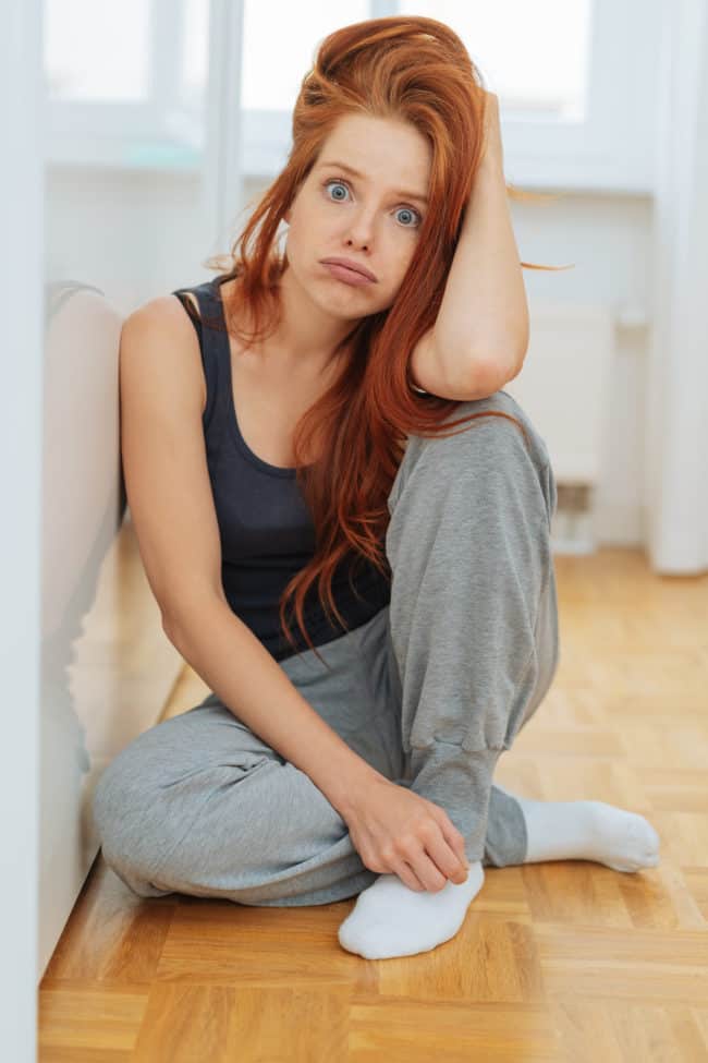 A woman sitting on the floor in front of a wall.