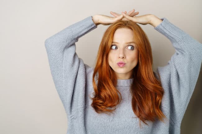 A woman with red hair holding her head up.