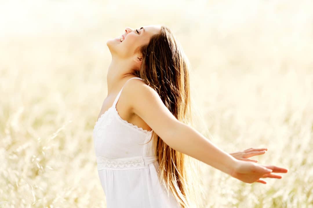 A woman in white dress with arms outstretched.