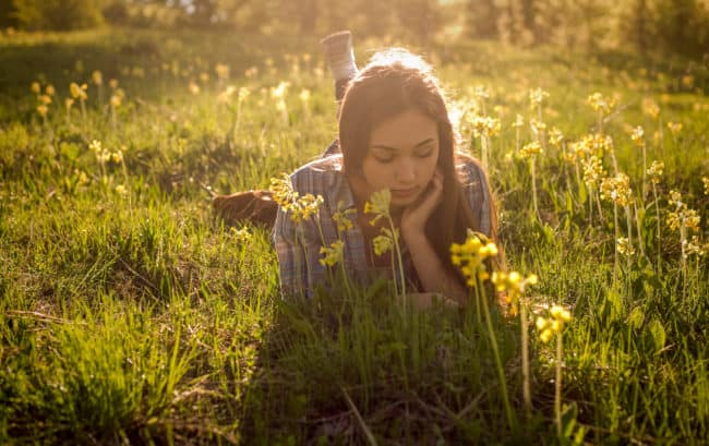 A woman laying in the grass with flowers.