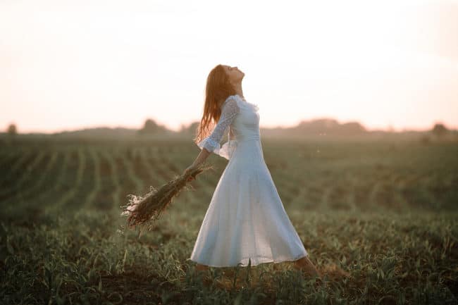 A woman in white dress holding an umbrella.