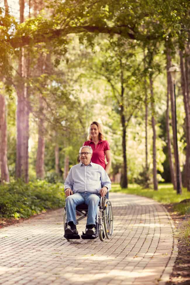 A man in a wheelchair with a woman on the back of him.